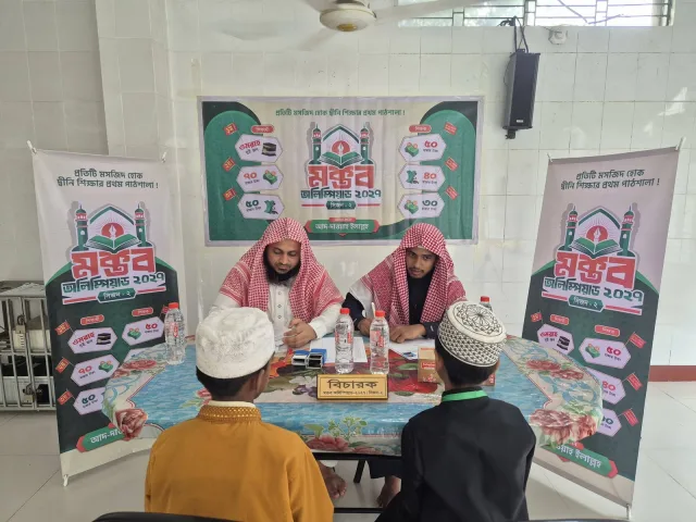মক্তব অলিম্পিয়াড সিজন-২-এর একটি পরীক্ষাকেন্দ্রে বিচারকদের সামনে অংশগ্রহণকারী শিক্ষার্থীদের মৌখিক মূল্যায়নের দৃশ্য।